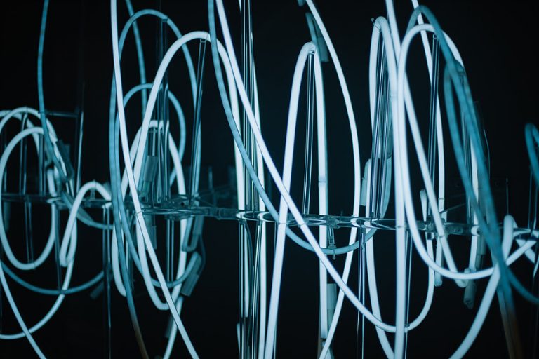 Close-up of glowing white neon light tubes arranged in abstract loops.